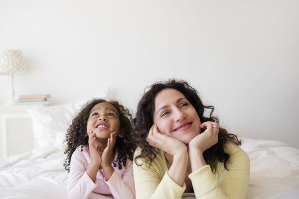 Mother and daughter daydreaming on bed