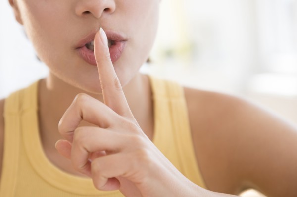 Close up of Hispanic woman shushing