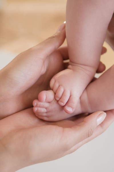 Close up of mother holding bare feet of baby
