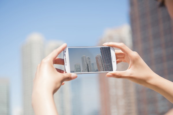 Hispanic woman photographing skyline with cell phone