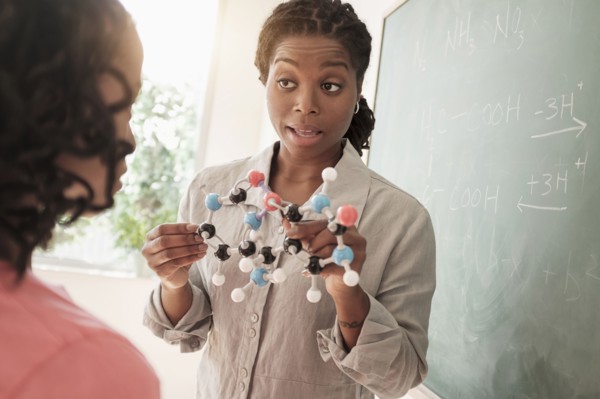 Black teacher showing molecular model to students