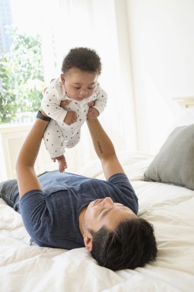 Father holding baby son on bed