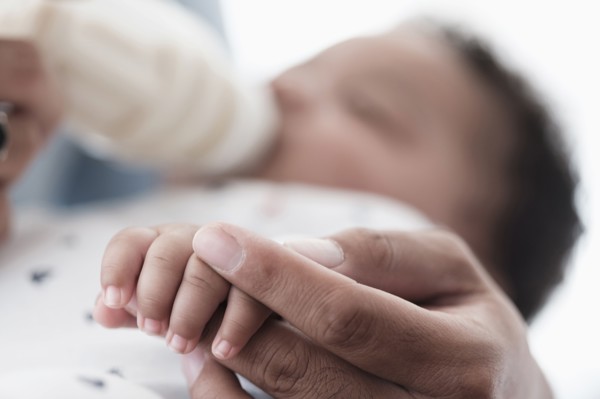Close up of father holding hand of baby son
