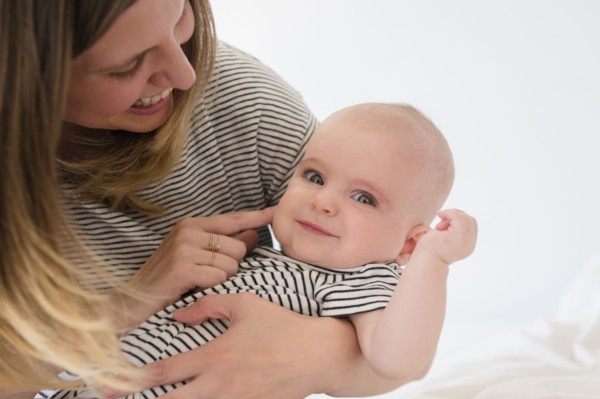 Caucasian mother holding baby daughter on bed