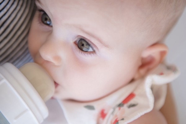 Caucasian mother feeding baby daughter