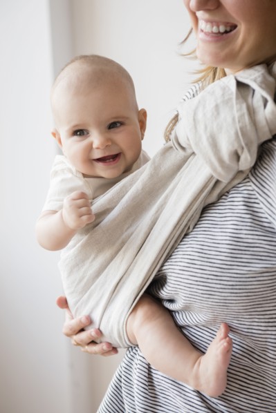 Caucasian mother holding baby daughter in sling