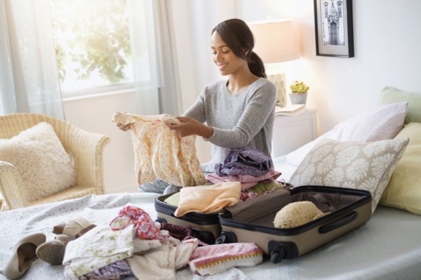 Mixed race woman packing suitcase in bed