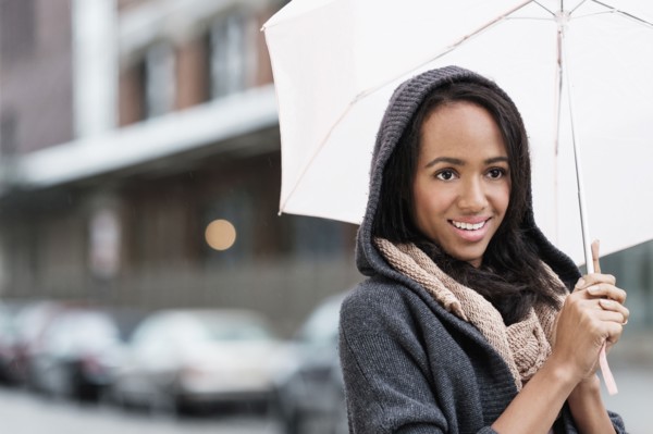 Mixed race woman carrying umbrella outdoors