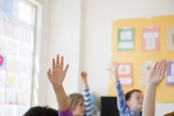 Students raising hands in classroom