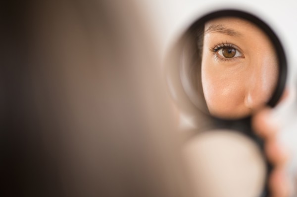 Mixed race woman admiring herself in compact mirror