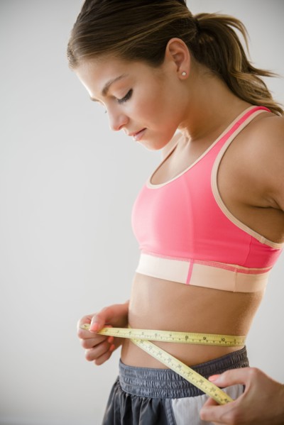 Mixed race woman measuring her waist