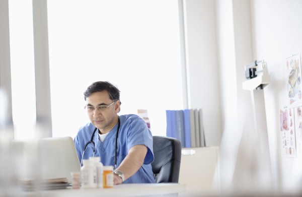 Mixed race doctor working on laptop