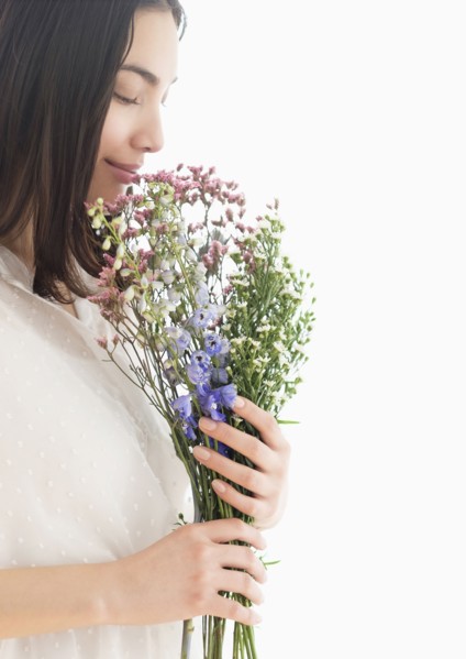 Hispanic woman smelling bouquet of flowers