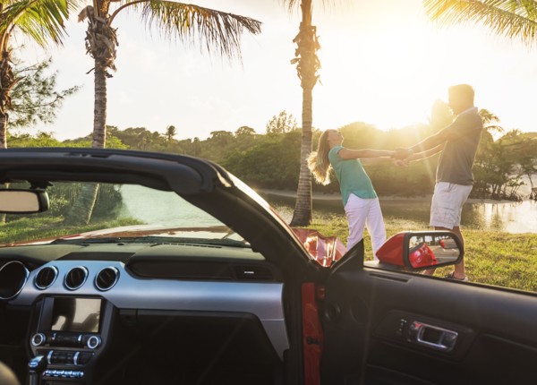 Caucasian couple dancing near convertible