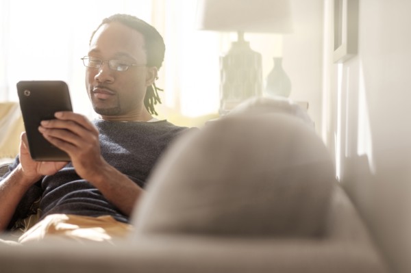 Black man using digital tablet on sofa