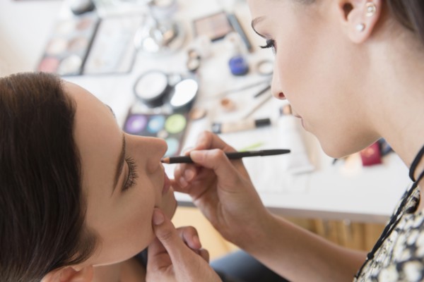 Woman having makeup applied by stylist