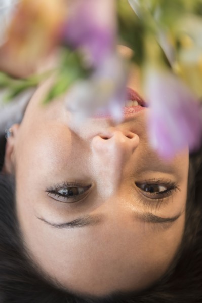 Face of smiling woman obscured by flowers