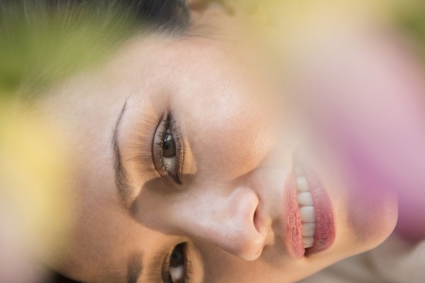 Face of smiling woman obscured by flowers