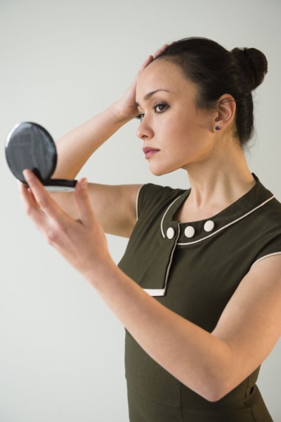 Businesswoman checking makeup in compact mirror