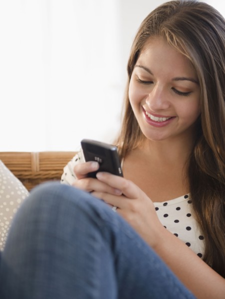 Smiling Indian woman text messaging on cell phone