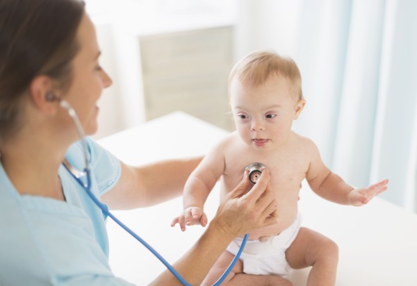 Caucasian doctor tending to baby girl with Down Syndrome