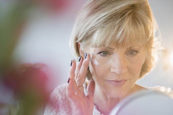 Older Caucasian woman applying moisturizer to face