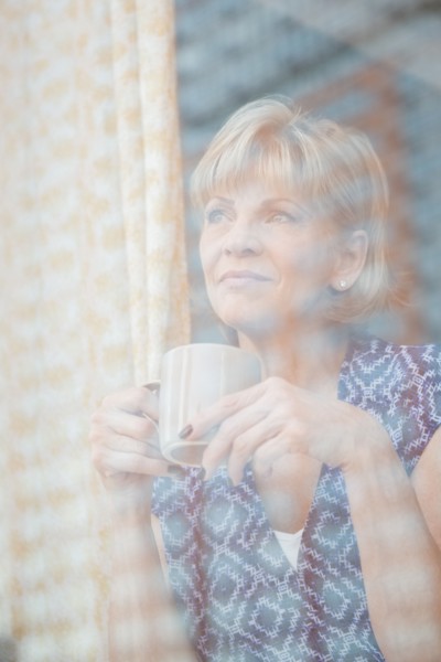 Older Caucasian woman drinking coffee at window