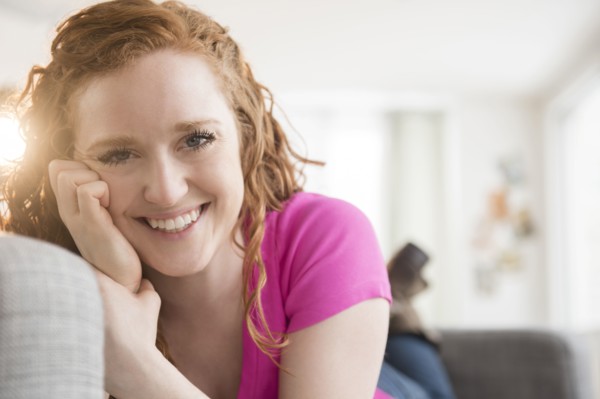 Smiling Caucasian woman laying on sofa