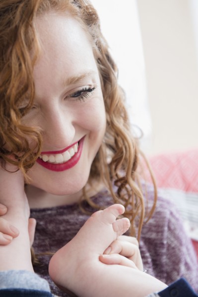 Caucasian woman holding foot of baby son
