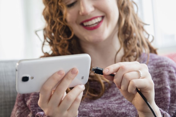 Caucasian woman connecting cord to cell phone