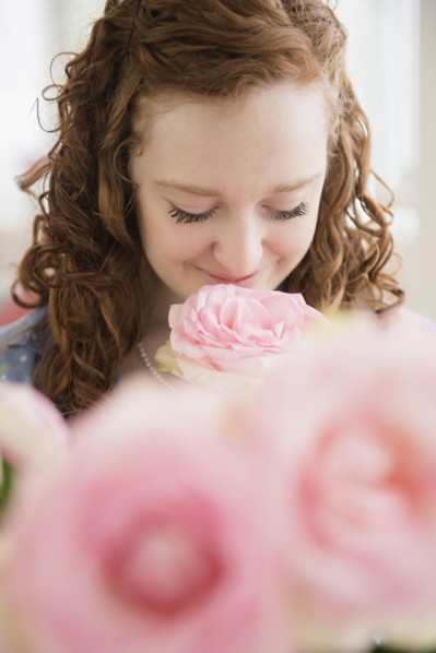 Caucasian woman smelling pink rose