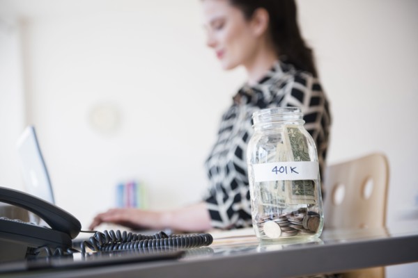 401k money jar on desk of Caucasian businesswoman