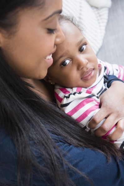 Black mother cuddling baby daughter