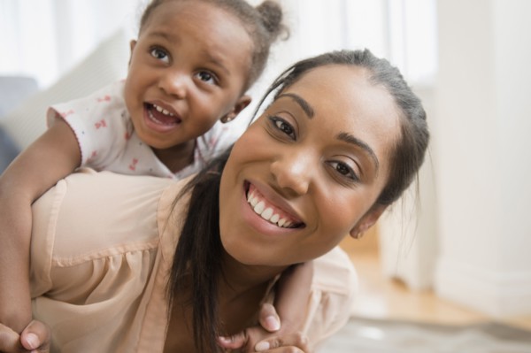 Black mother carrying baby daughter piggyback
