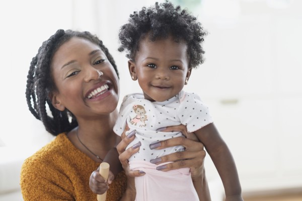 Smiling Black mother holding baby daughter