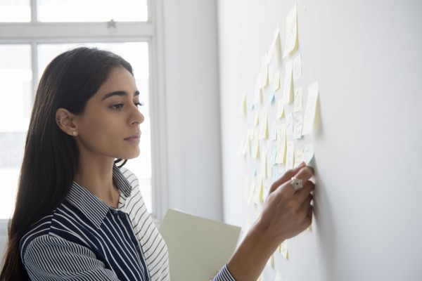Indian businesswoman reading adhesive notes in office