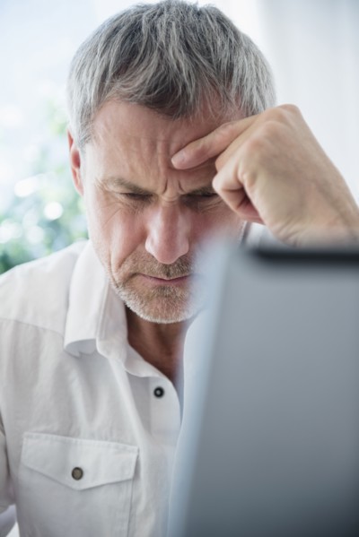 Frustrated older Caucasian man using laptop