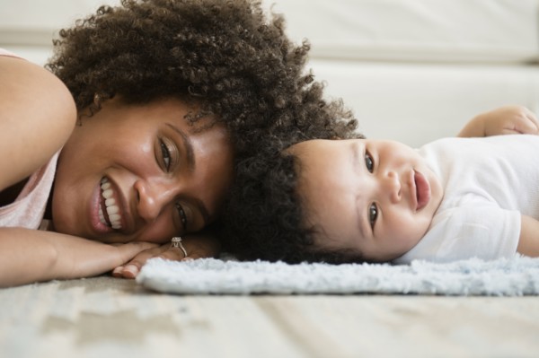 Mother and baby son laying head to head on floor