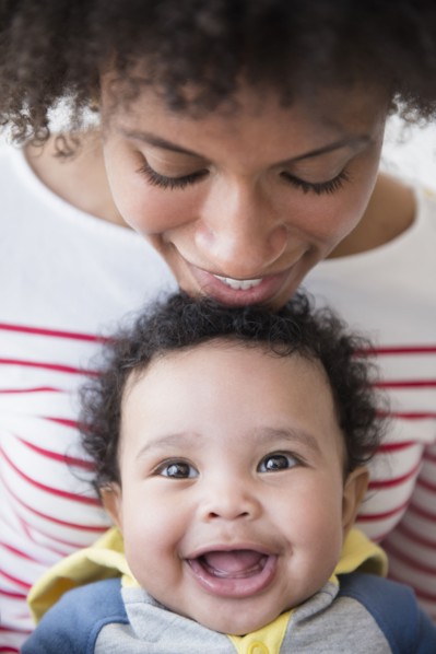 Smiling mother leaning chin on head of baby son