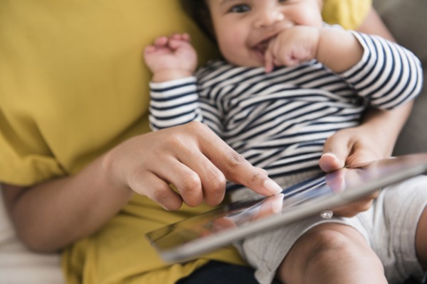 Mother holding baby son using digital tablet