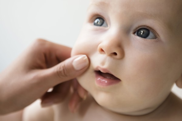 Hand of mother pinching cheek of baby son