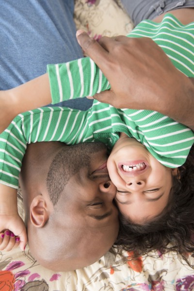 Father kissing daughter on bed