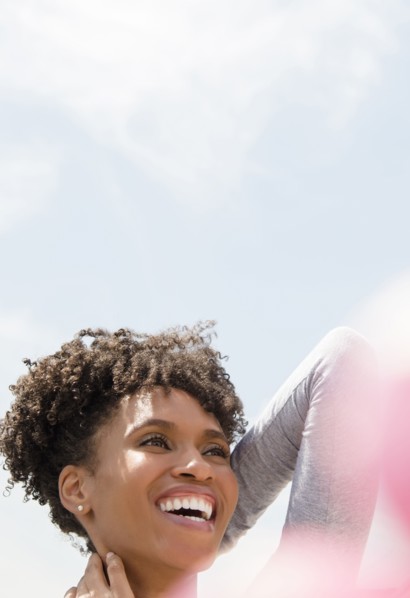 Smiling Black woman rubbing neck outdoors