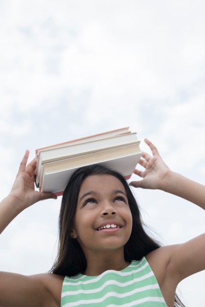 Mixed Race girl balancing books on head