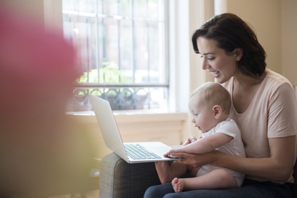 Caucasian mother holding baby in lap using laptop