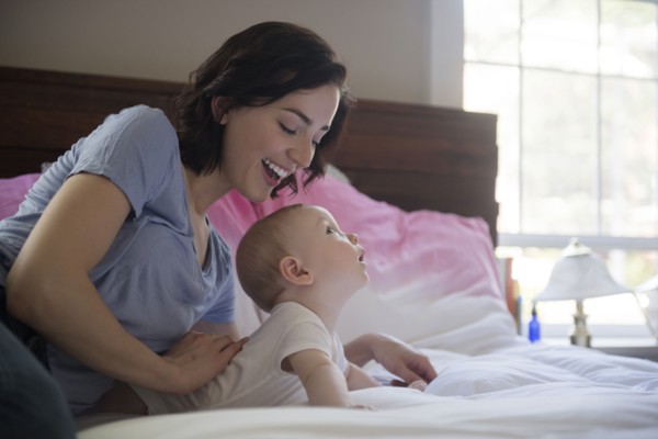 Caucasian mother and baby son laying on bed