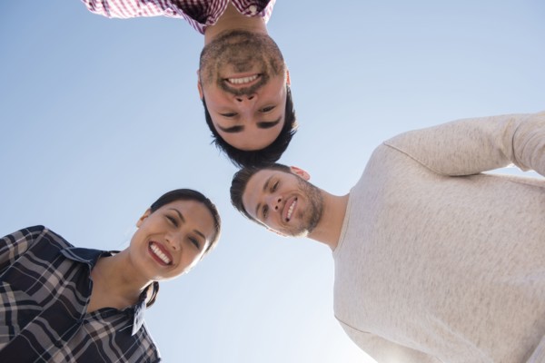 Smiling friends losing under blue sky