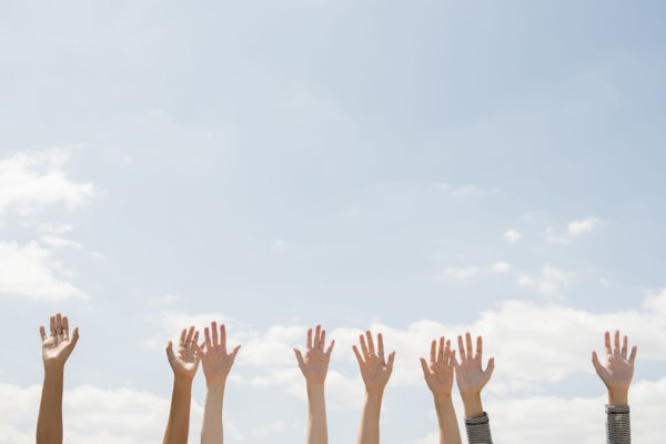 Raised hands of women outdoors