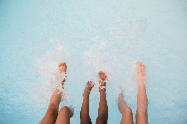 Legs of girls splashing feet in swimming pool