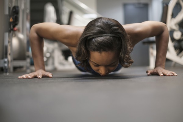 Mixed Race woman doing push-up on floor at gymnasium